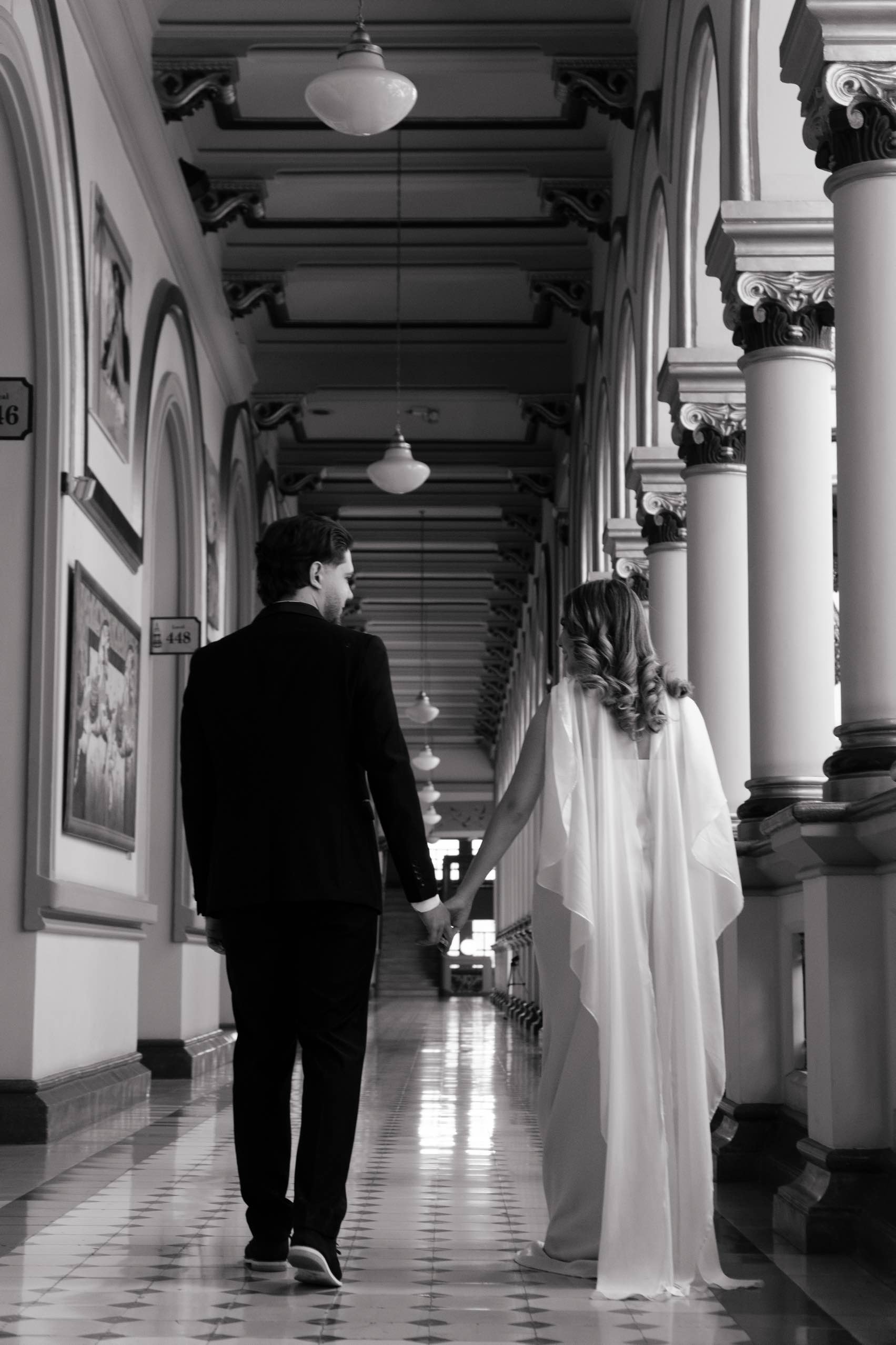 La pareja caminando de la mano por el corredor en blanco y negro